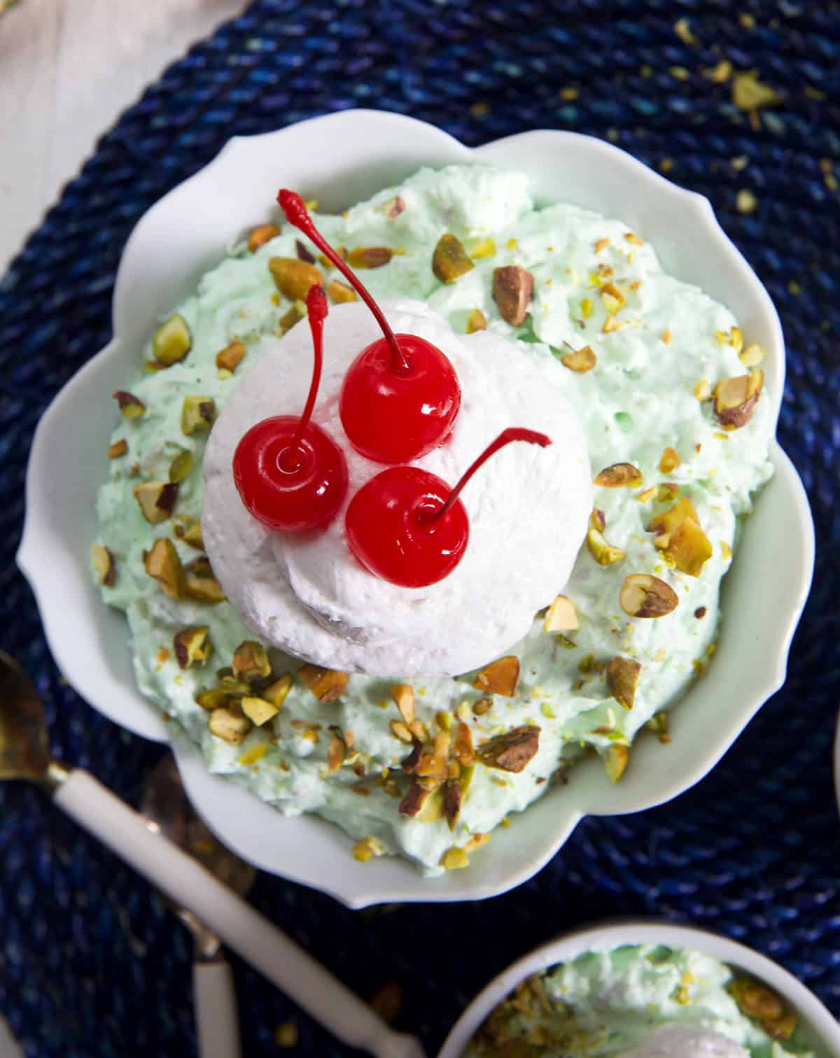 Whipped cream and cherries top a bowl full of watergate salad.