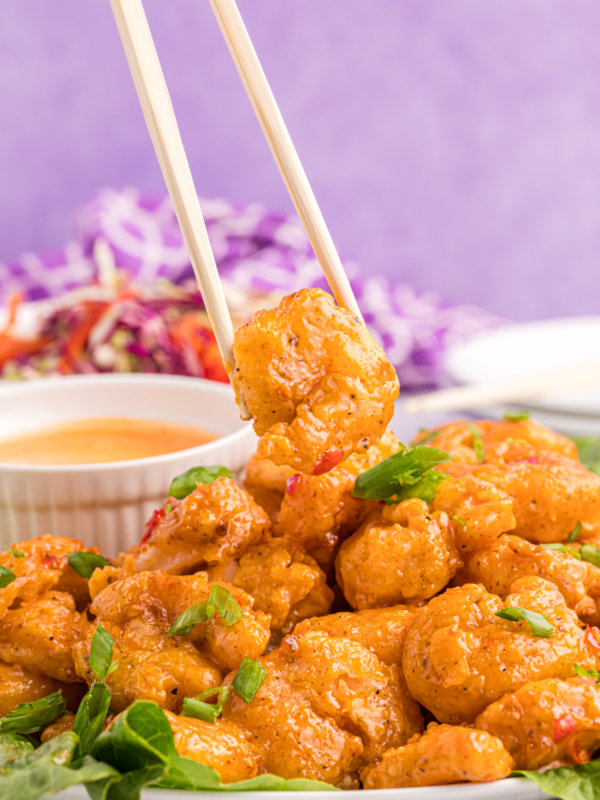 A shrimp is being lifted by a pair of chopsticks.