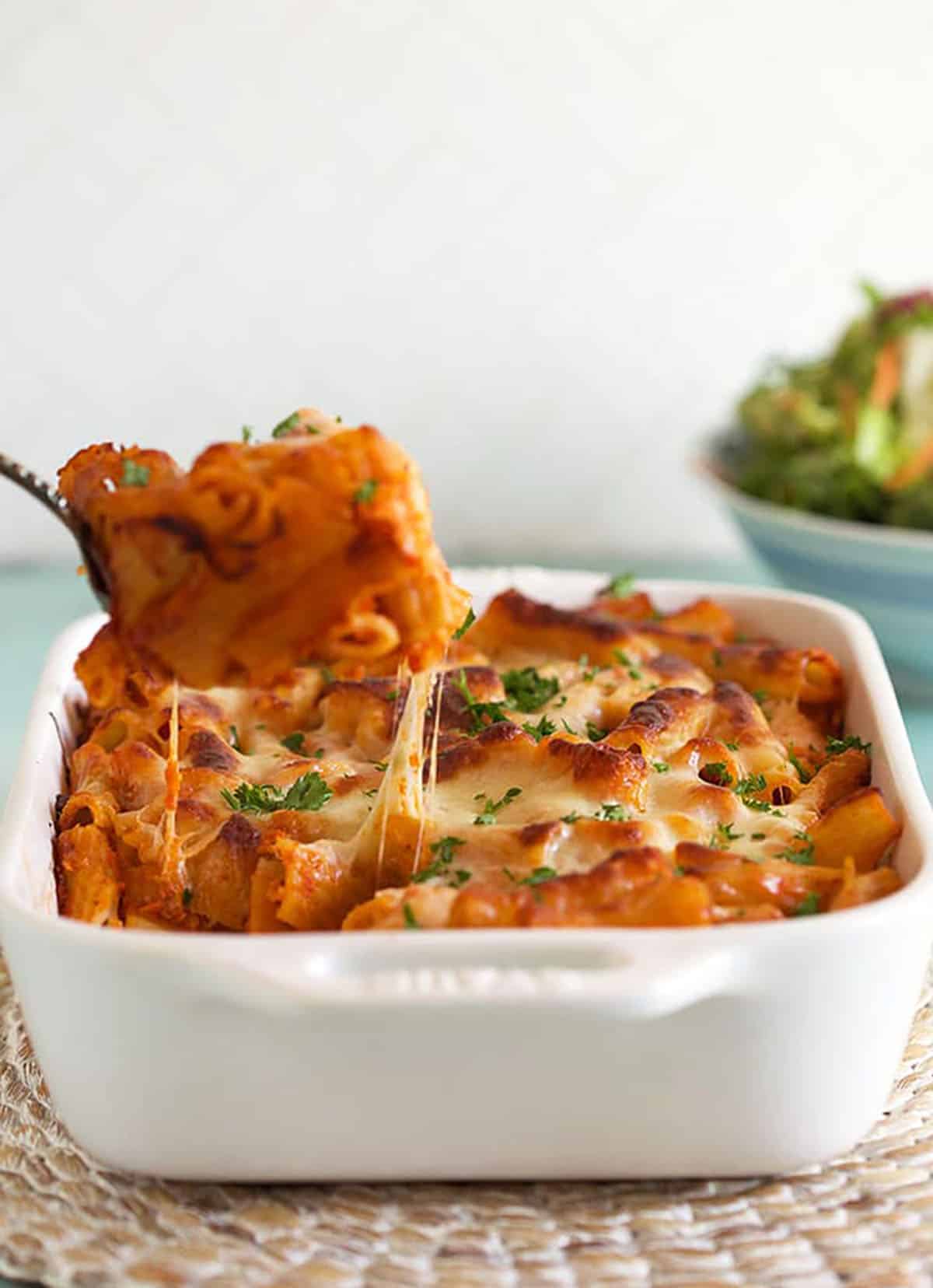 Baked Rigatoni Bolognese being served with a cheese pull into the dish.