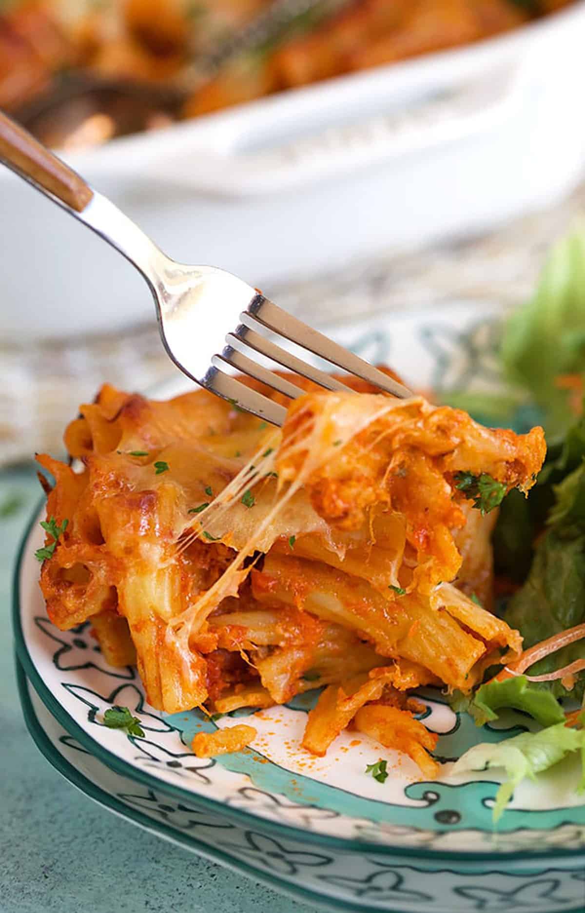 Baked Rigatoni on a plate with a fork taking a bite.