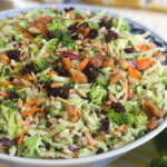 A blue and white bowl is filled to the rim with broccoli slaw.