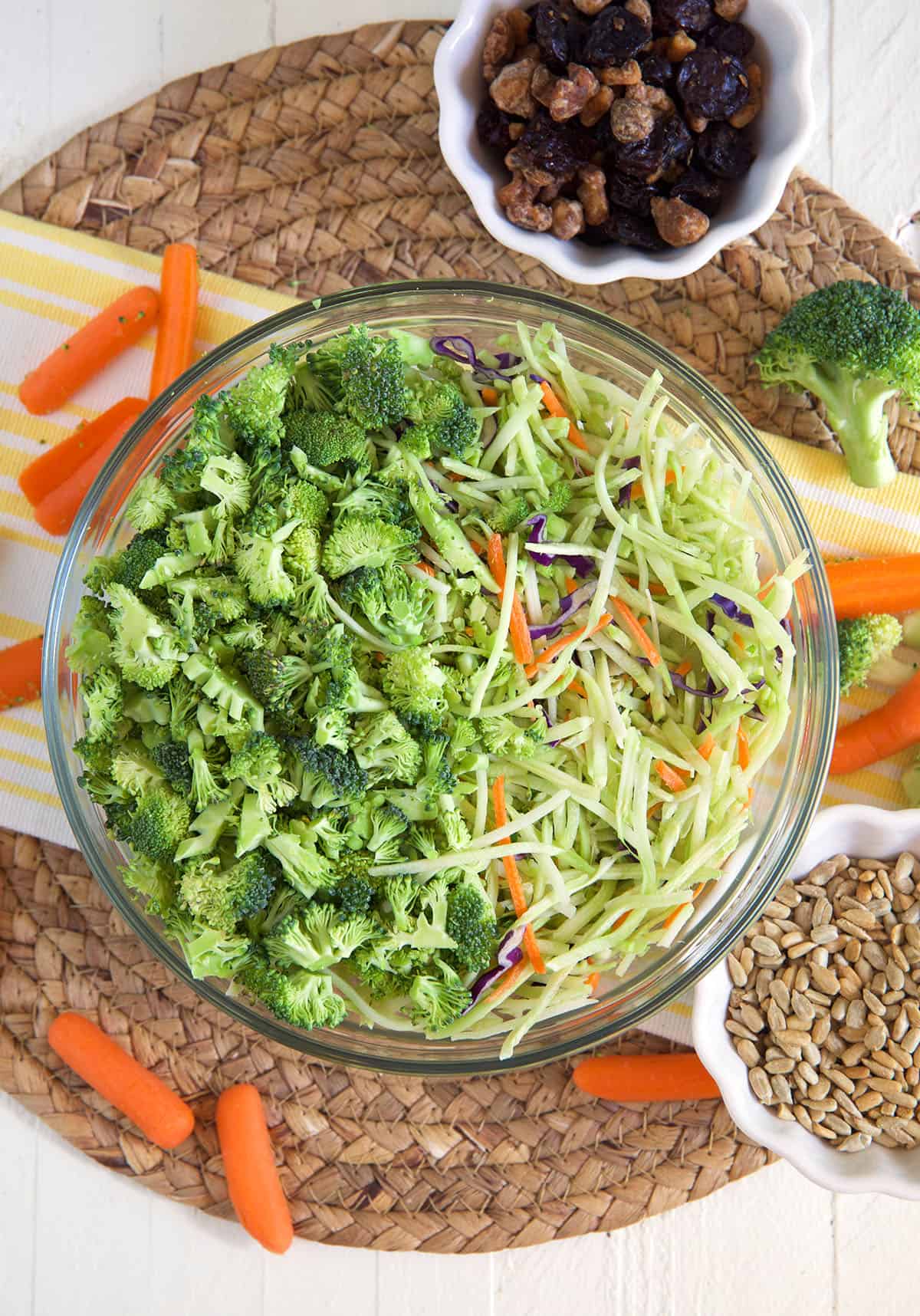 A large bowl is filled with the ingredients for broccoli slaw.
