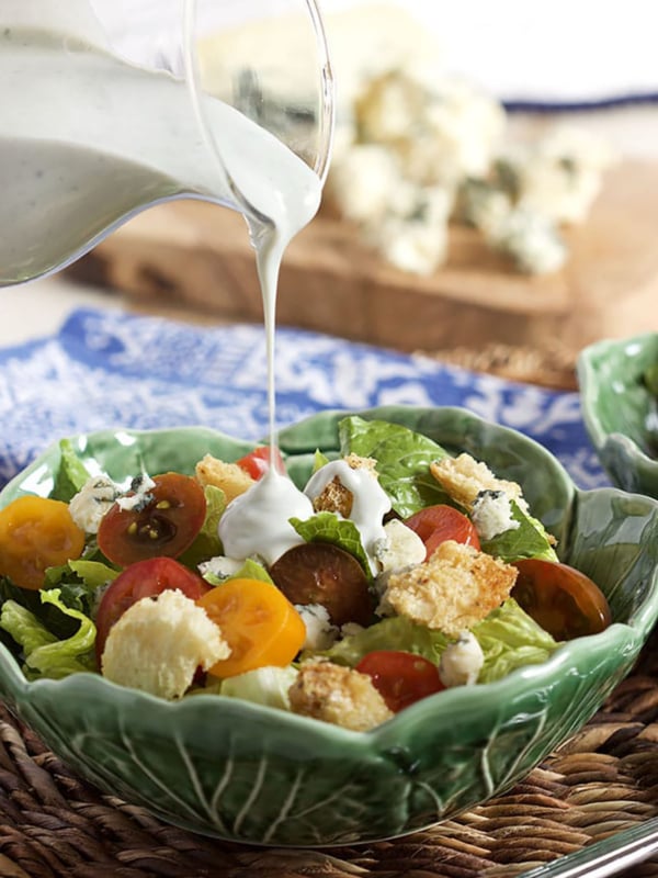 Buttermilk Blue Cheese Dressing being poured over a garden salad