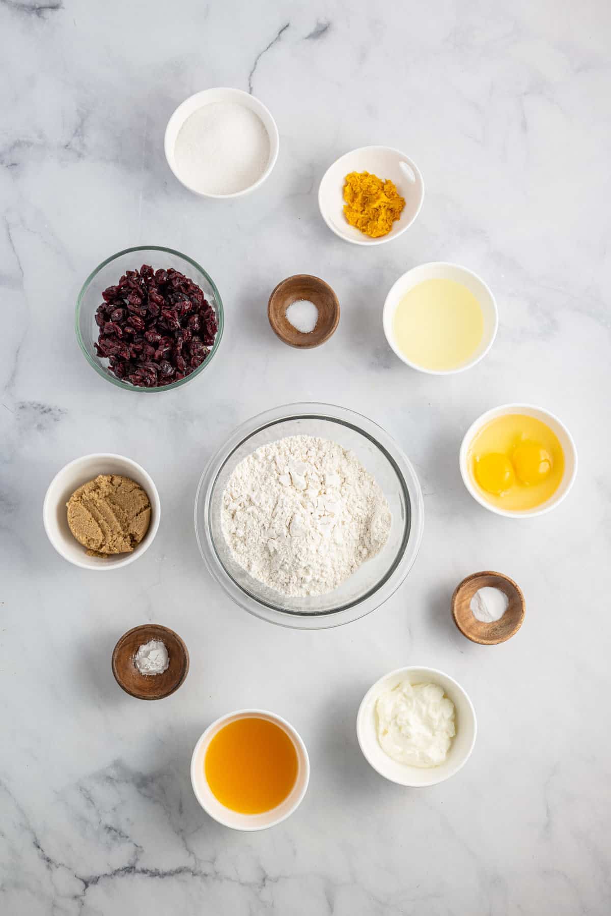 The ingredients for cranberry orange muffins are presented on a white surface.