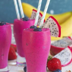 Several vibrant colored smoothies are presented on a white surface.