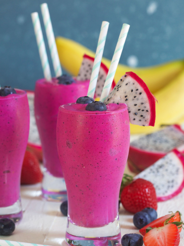 Several vibrant colored smoothies are presented on a white surface.