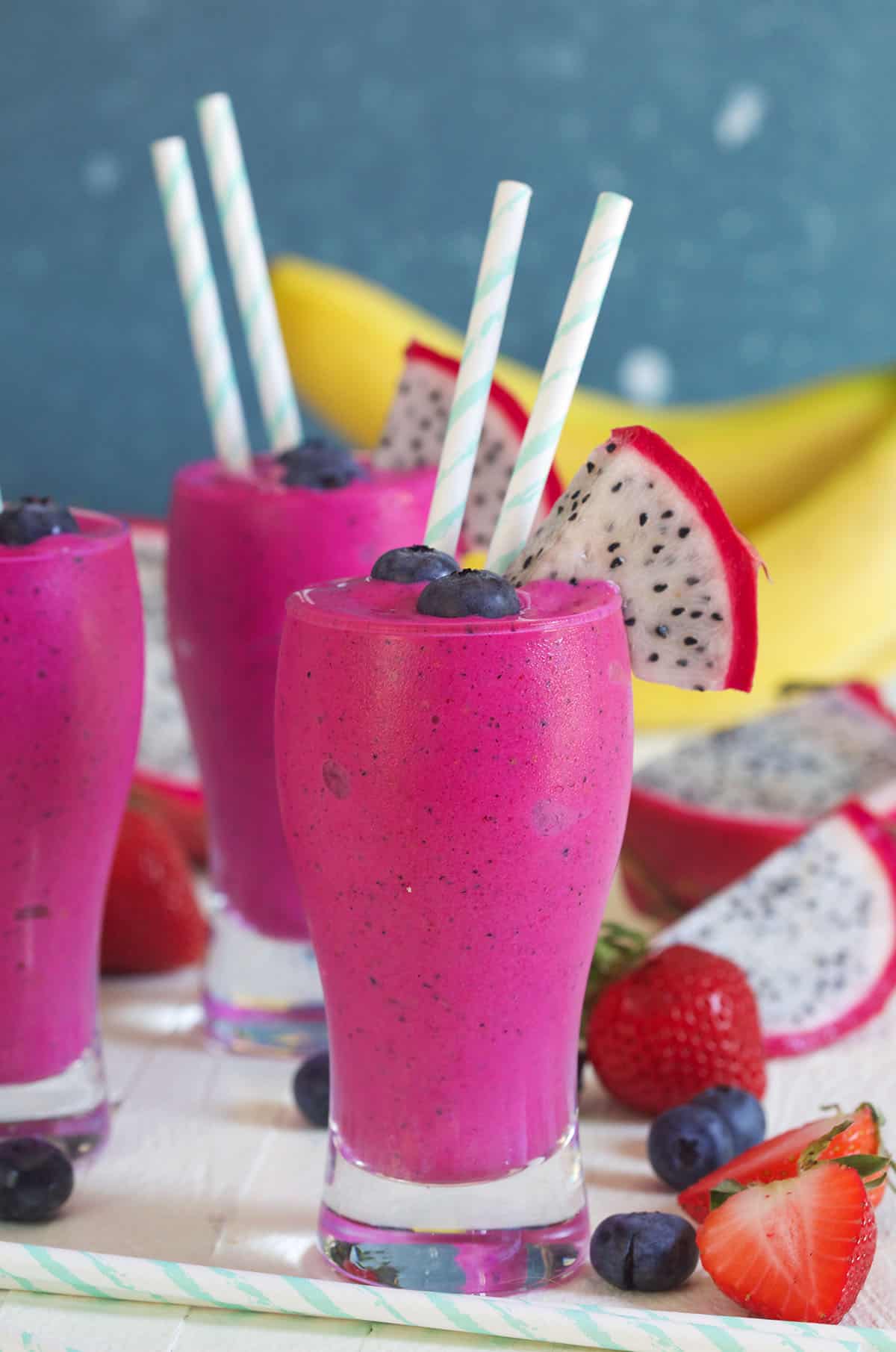 Several vibrant colored smoothies are presented on a white surface.