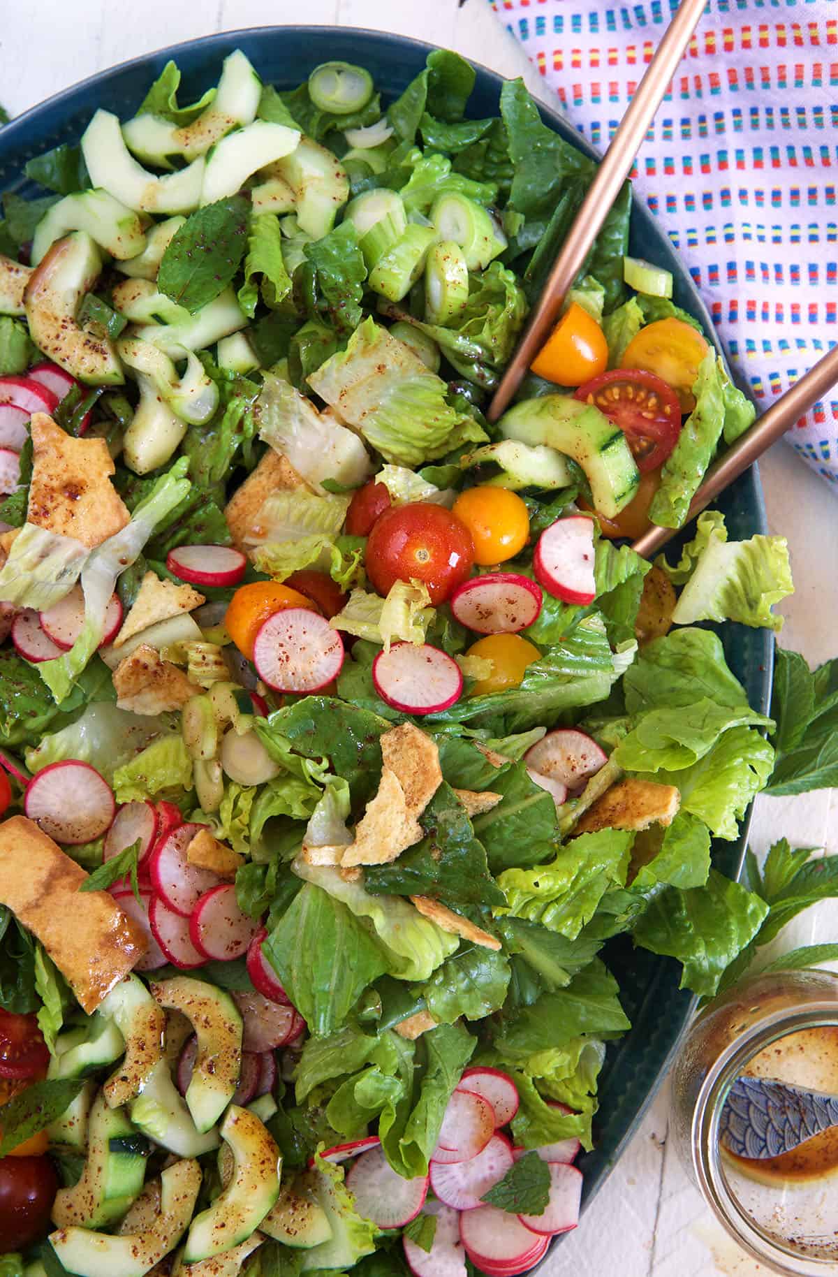 A tossed salad is presented in a large oval shaped serving dish.
