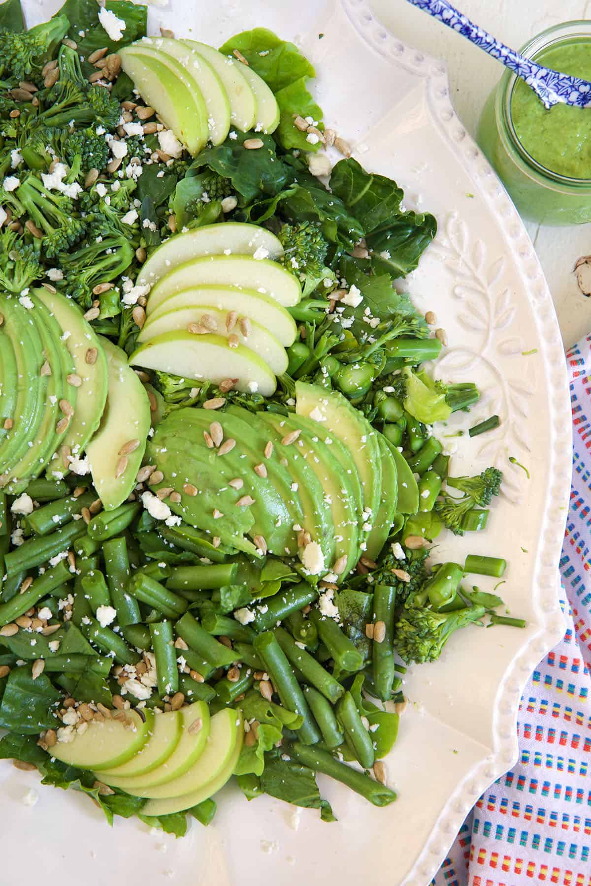 A green goddess salad is presented in a white serving bowl.