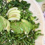 A white bowl is filled to the brim with green goddess salad.