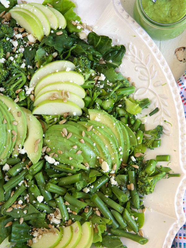 A white bowl is filled to the brim with green goddess salad.