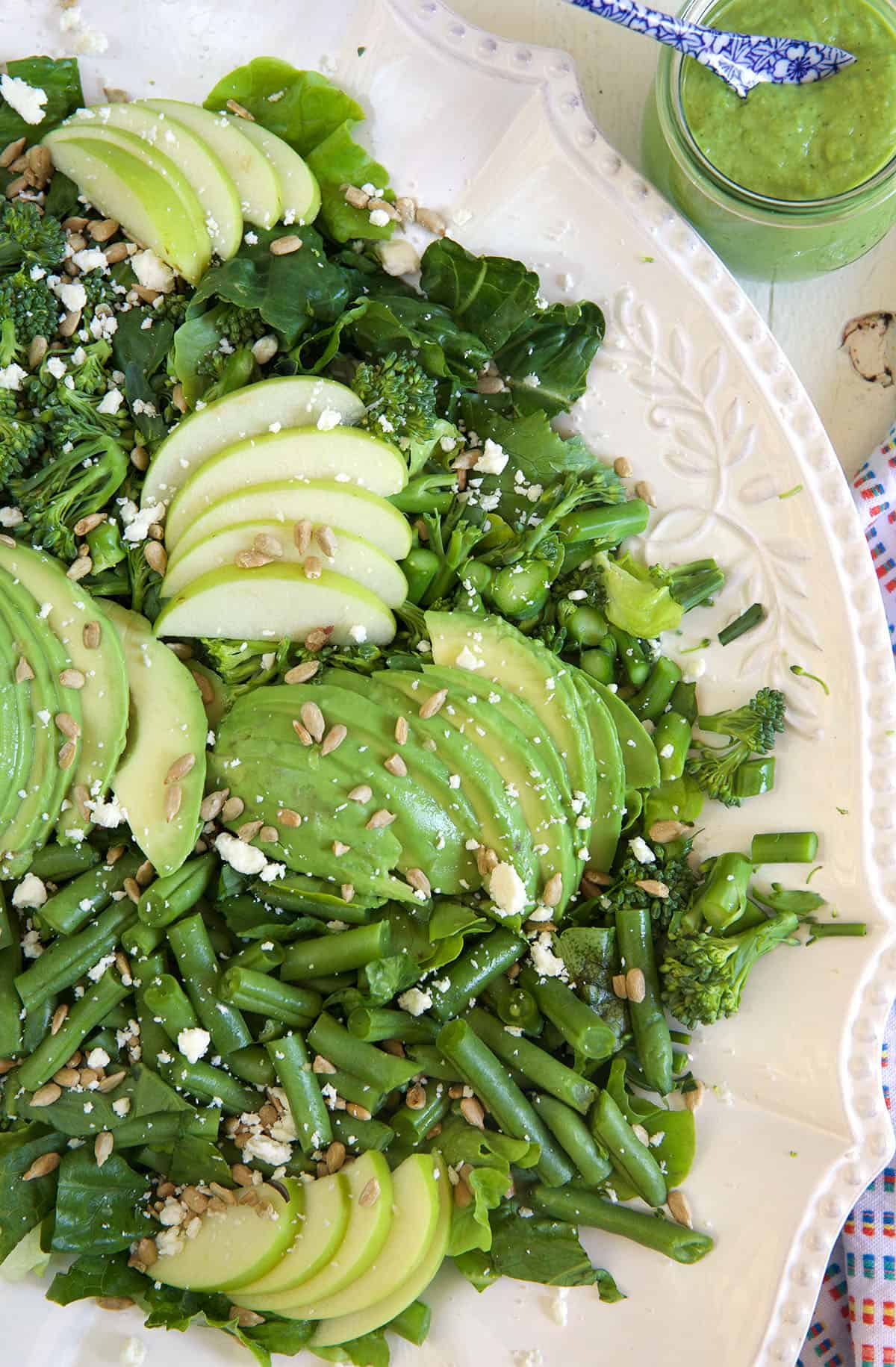 A white bowl is filled to the brim with green goddess salad.