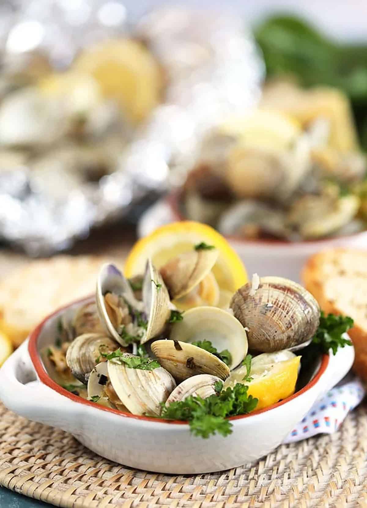 Grilled Clams with basil and lemons in a white ramekin 