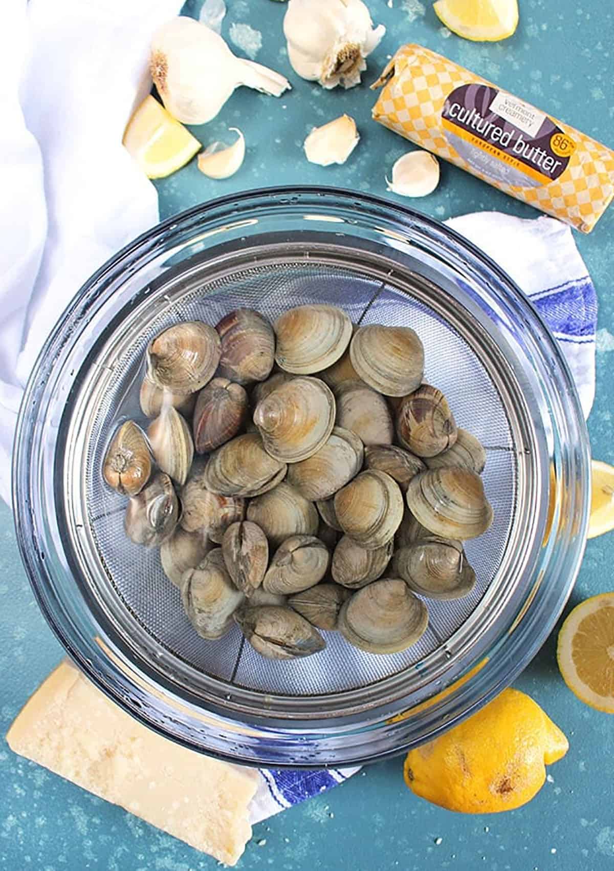 Clams soaking in a glass bowl with water.
