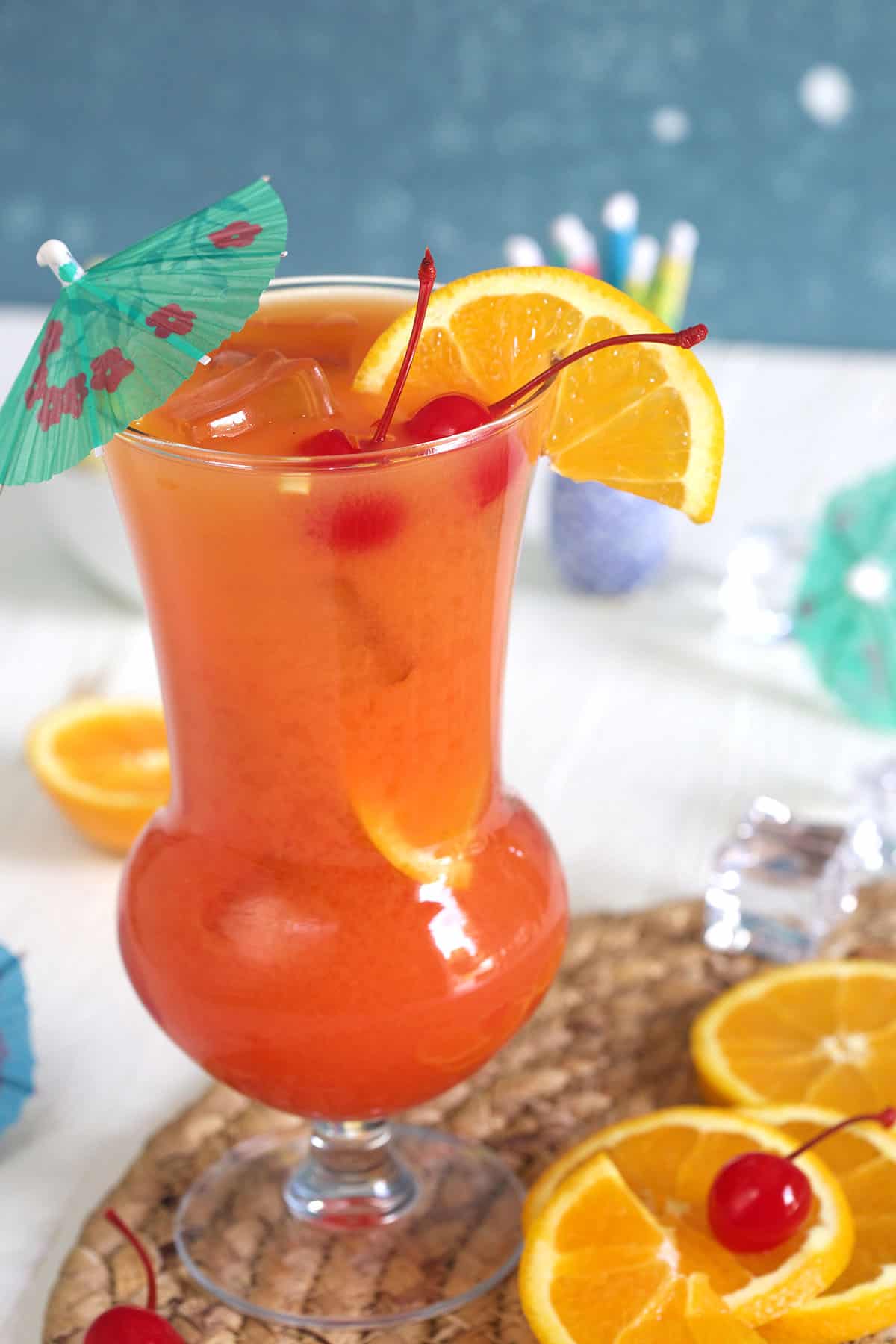 Several orange slices are placed next to a full hurricane glass.