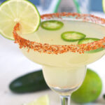 A margarita is topped with jalapeno slices and a lime round.