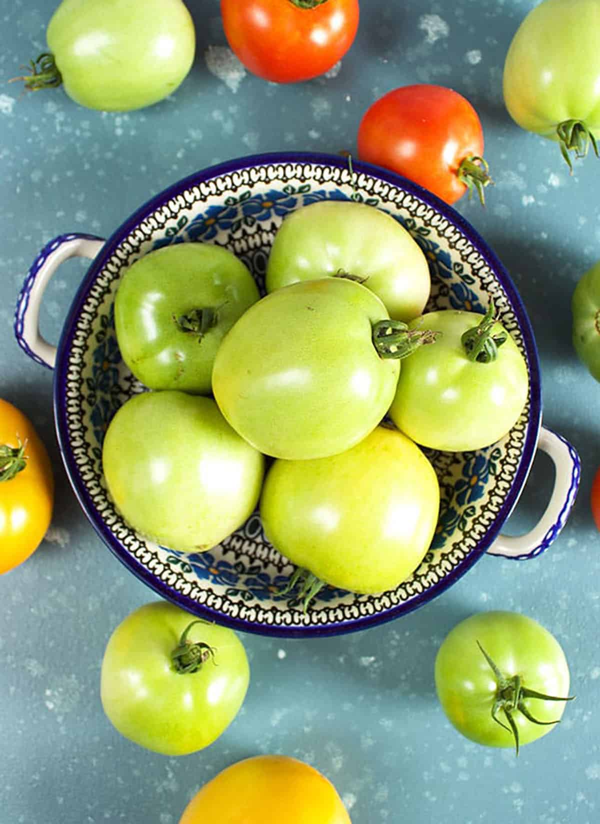 A bowl of green tomatoes on a blue background