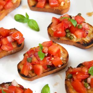 Slices of crostini are topped with a tomato bruschetta mixture.
