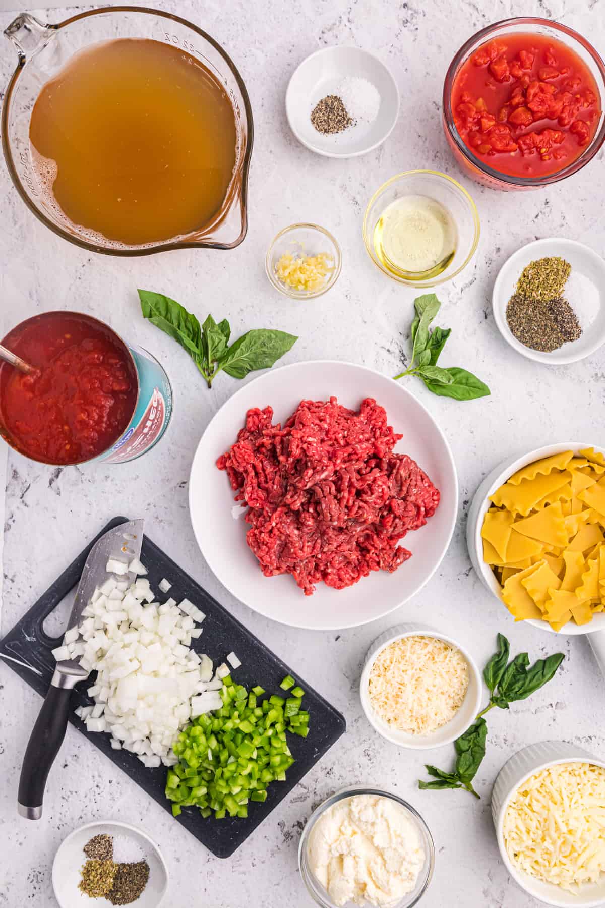 The ingredients for lasagna soup are placed on a white countertop.