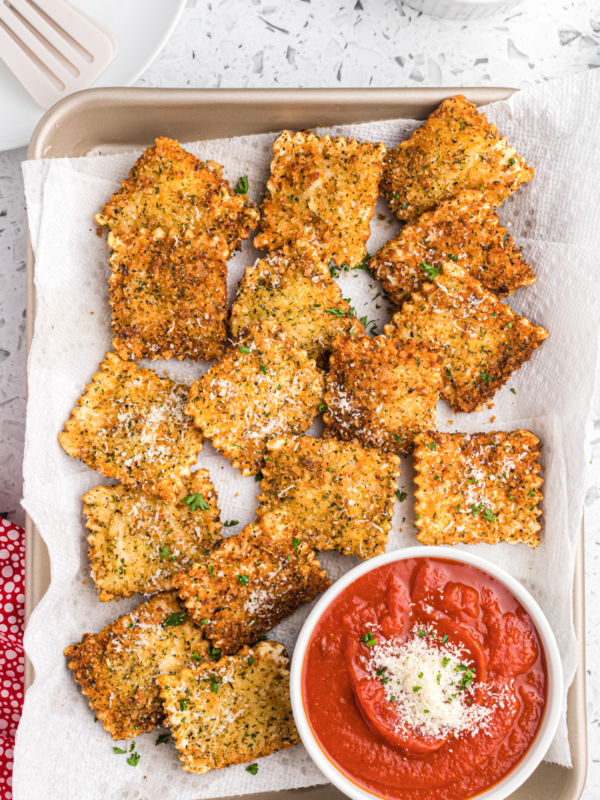 Fried ravioli is presented next to a small bowl of marinara sauce.