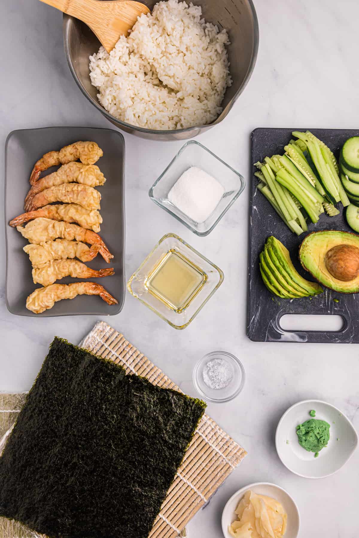 The ingredients for shrimp tempura roll are placed on a white countertop. 