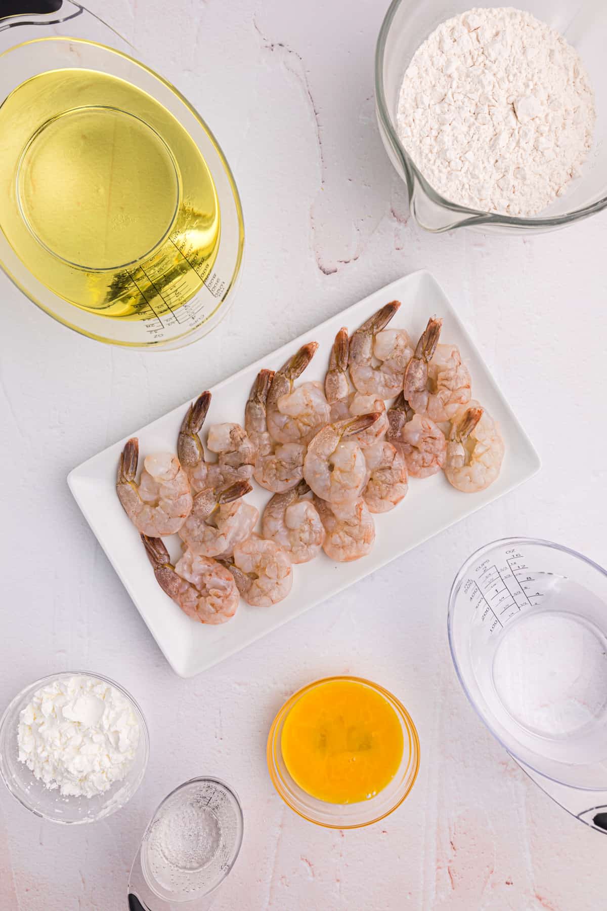 The ingredients for shrimp tempura are placed on a white surface.