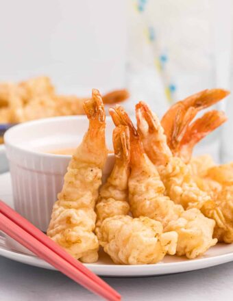 Several fried shrimp are placed next to dipping sauce.