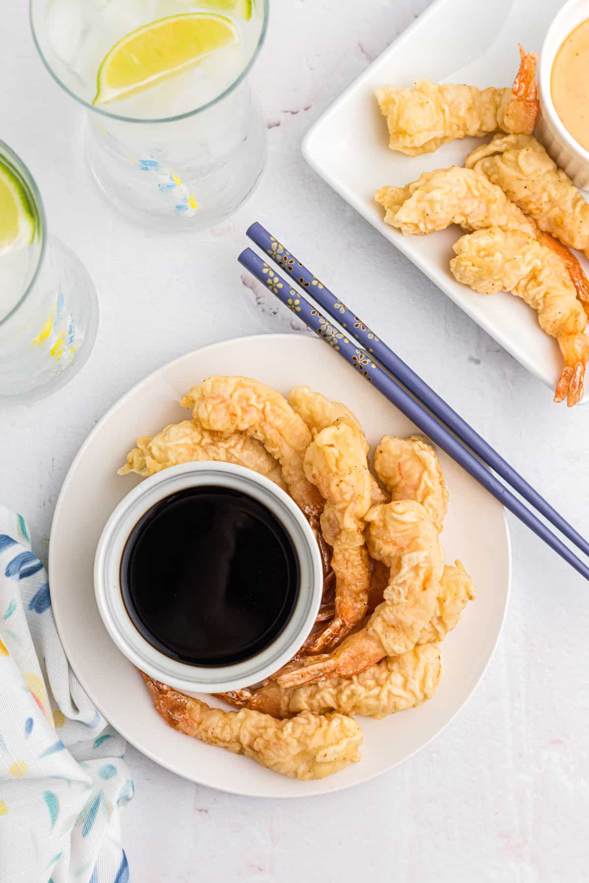 Several fried shrimp are placed around a small bowl filled with soy sauce.