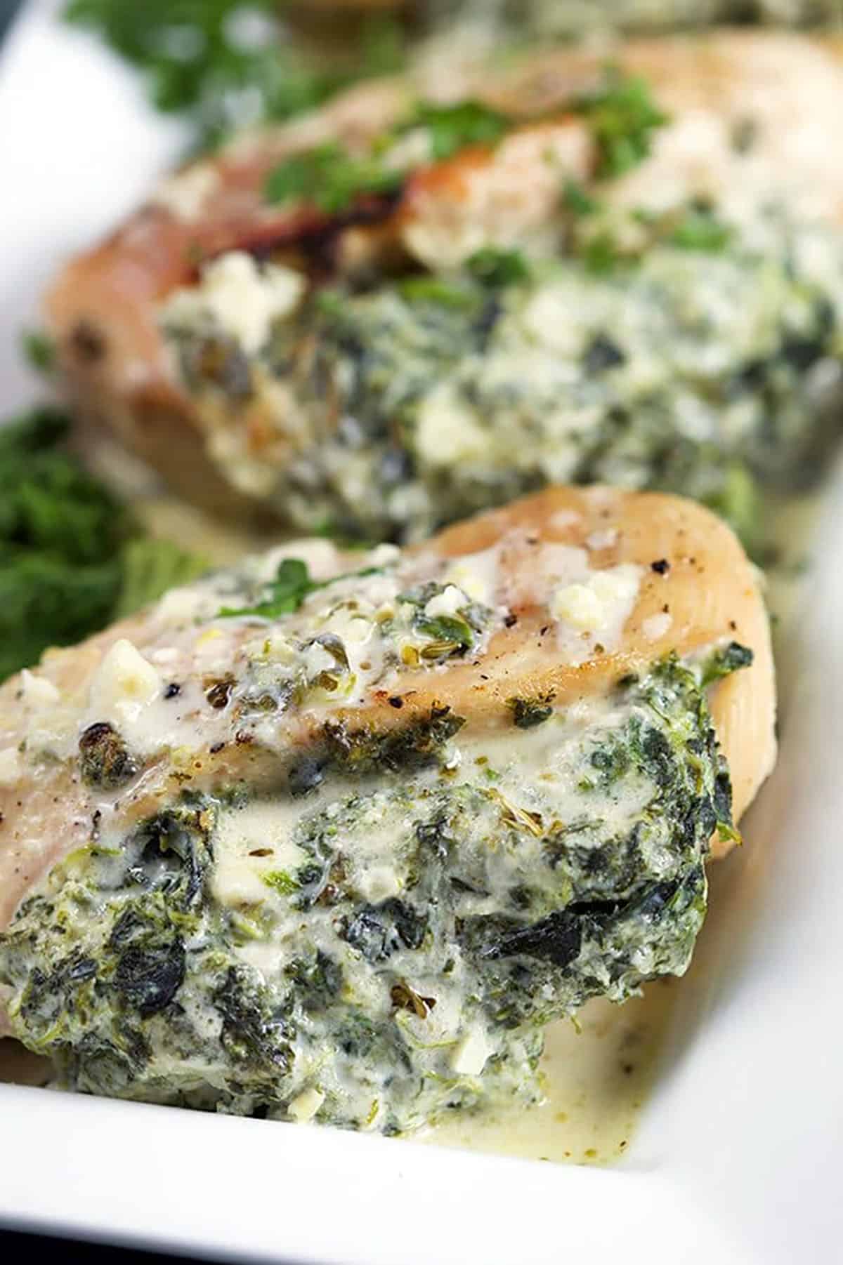 Cheesy Spinach Stuffed Chicken Breast close up on a white platter.