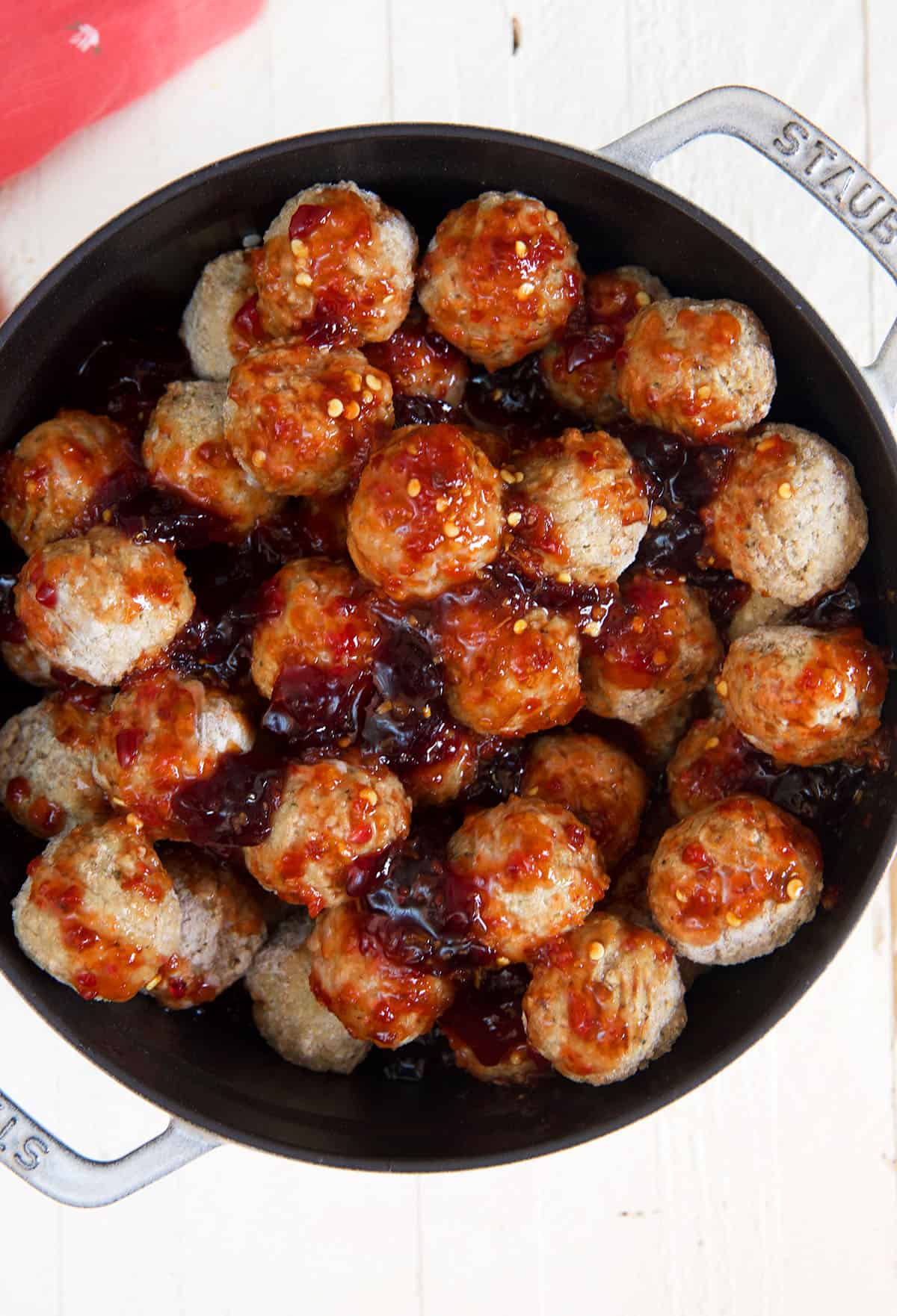 Frozen meatballs in a pot are mixed with jelly and chili garlic sauce.