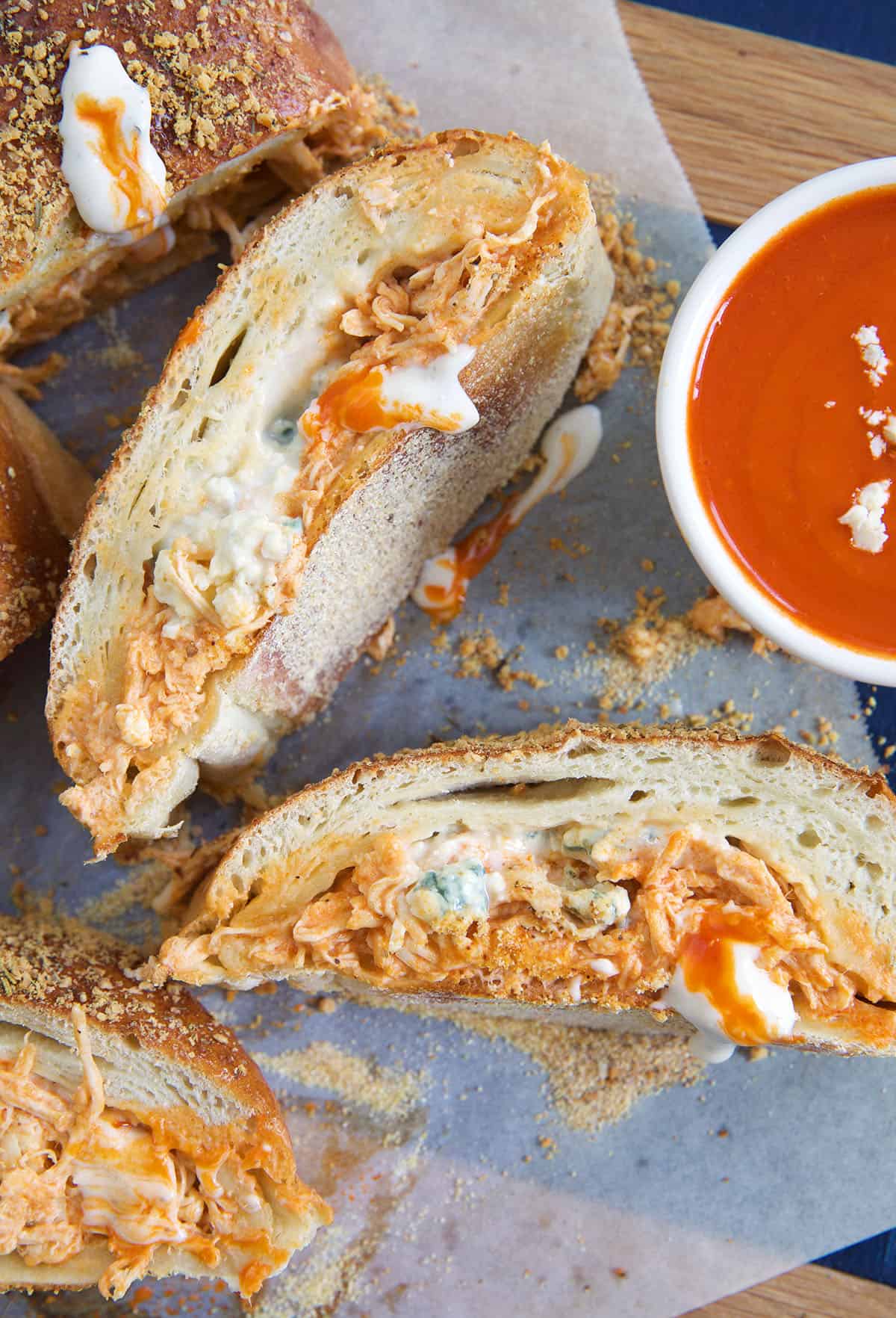 Several slices of stromboli are placed next to a bowl of dipping sauce.