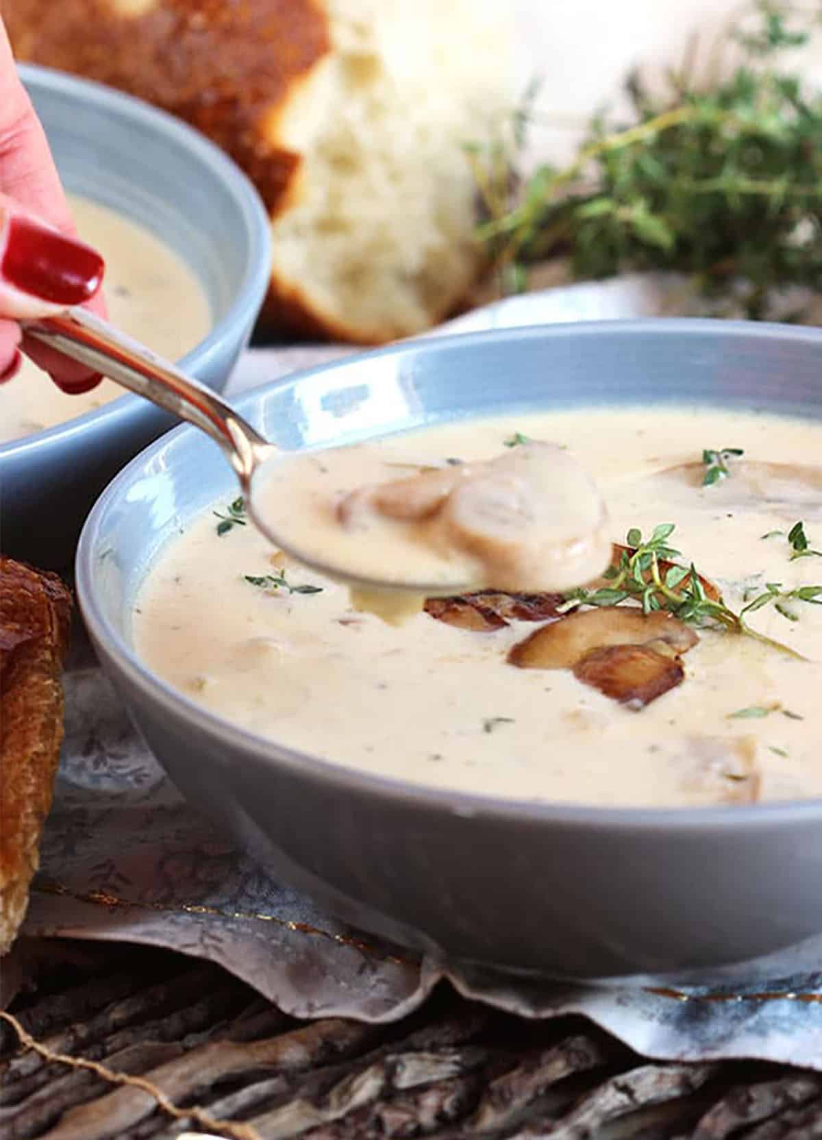 cream of mushroom soup with a spoon full of soup above the bowl