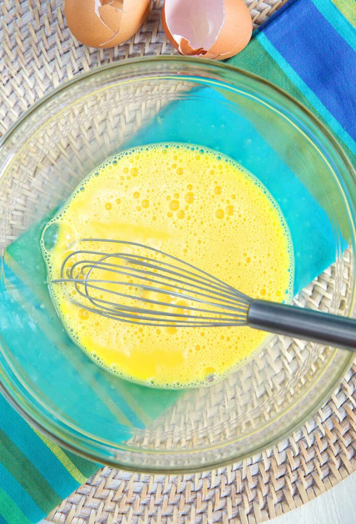 Eggs have been whisked together in a glass bowl. 