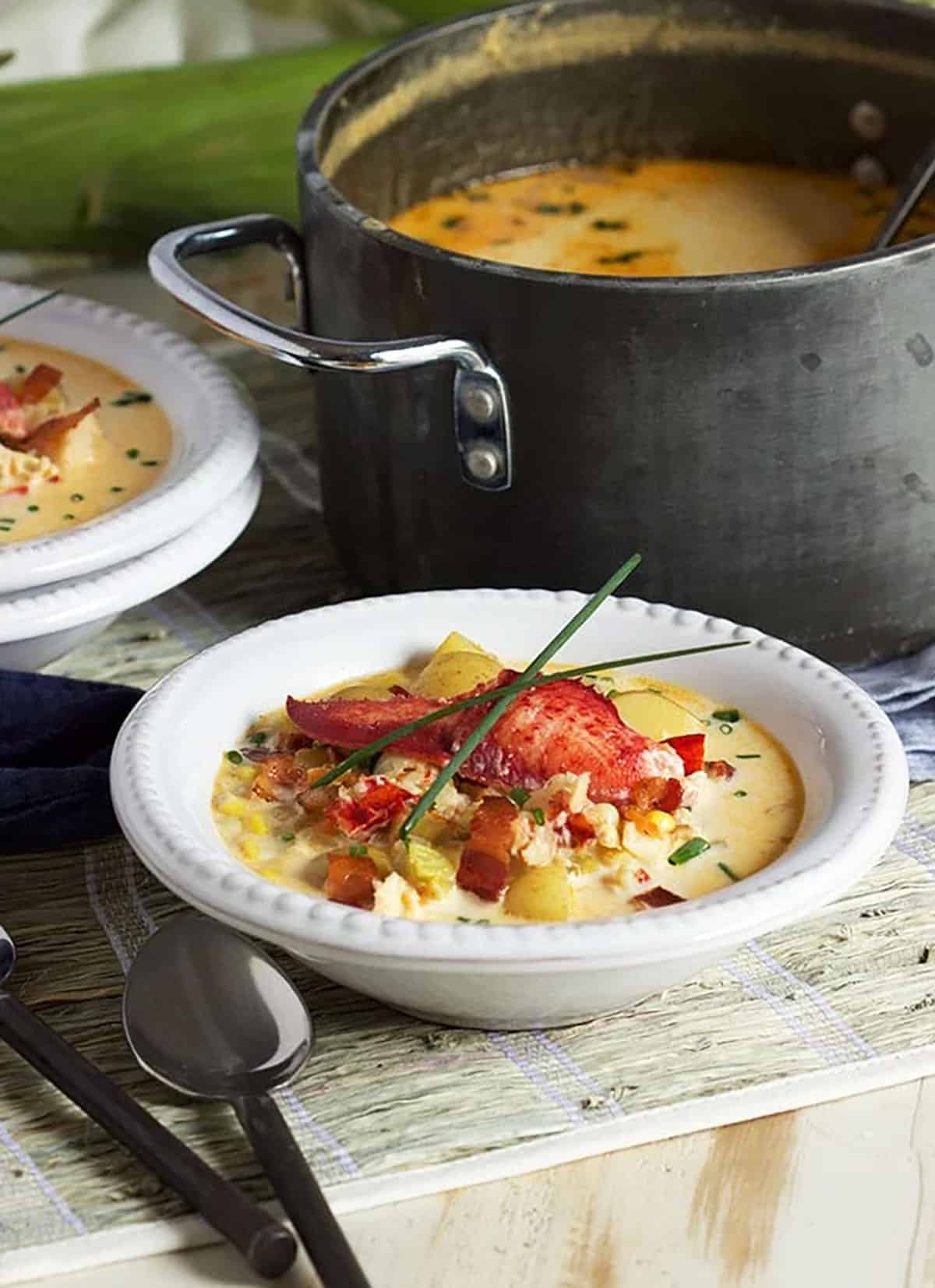 lobster corn chowder in a white bowl on a seagrass place mat.