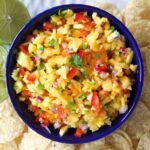 A blue bowl is filled with mango salsa.