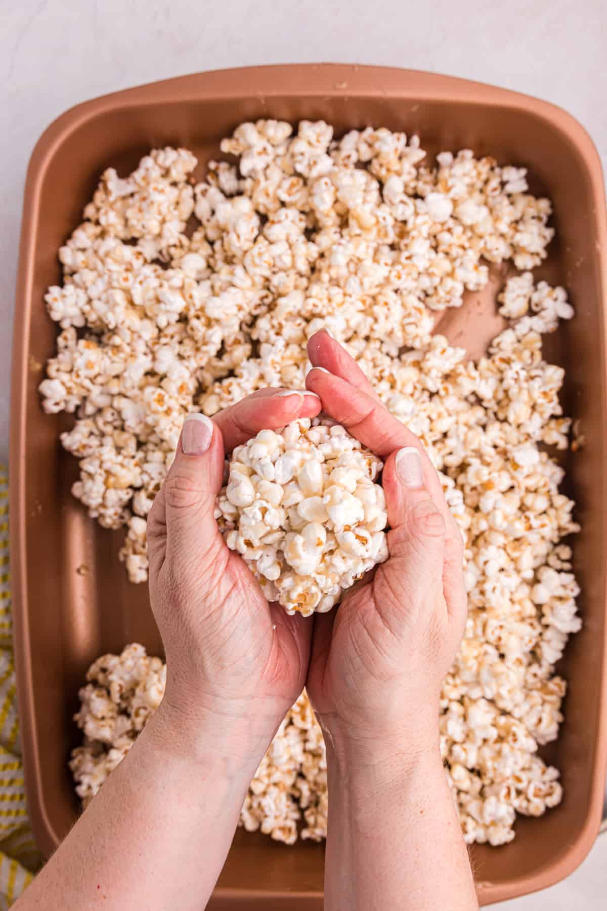 A popcorn ball is being formed by two hands.