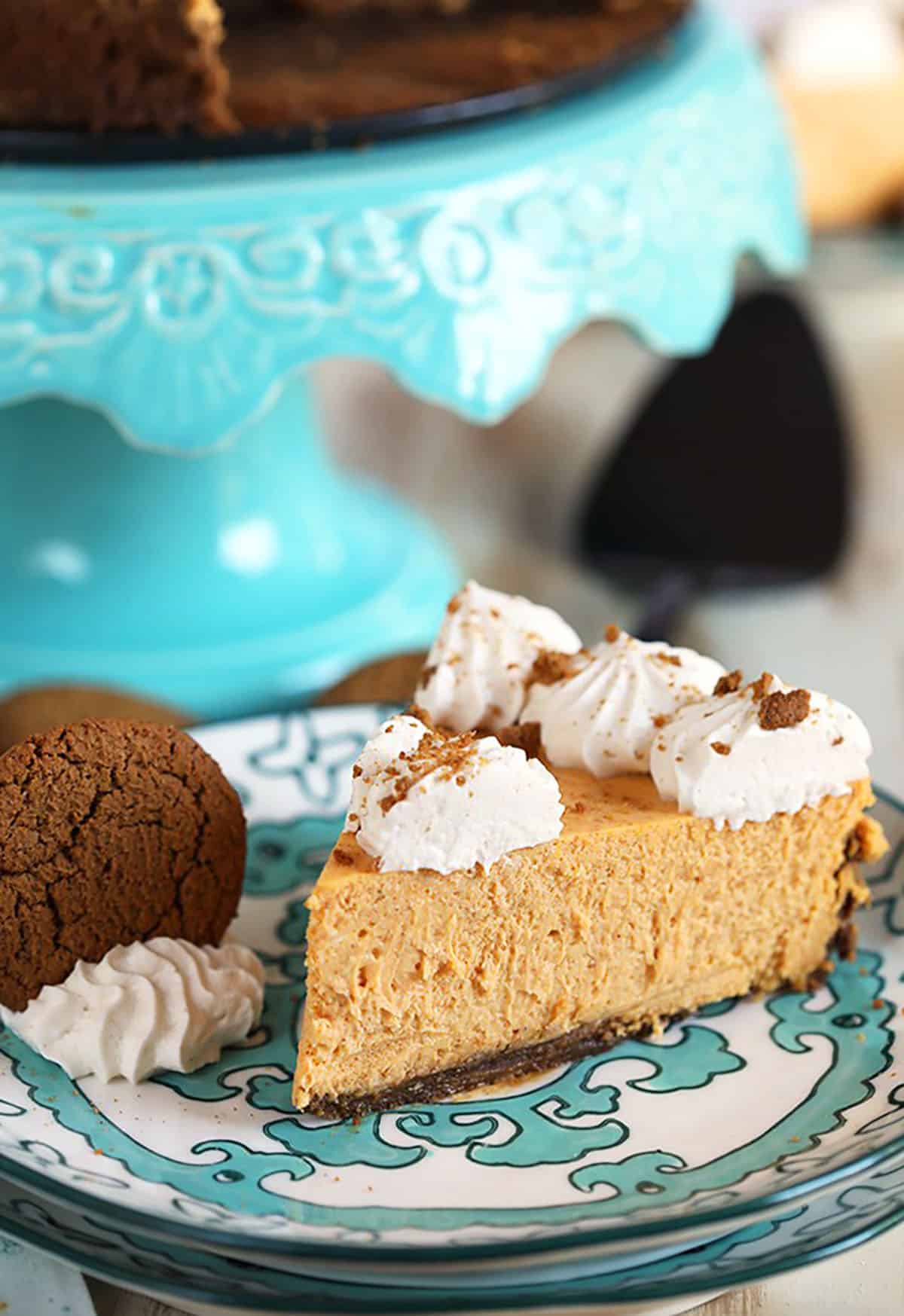 Pumpkin Cheesecake slice on a decorative plate with a gingersnap cookie on the side.