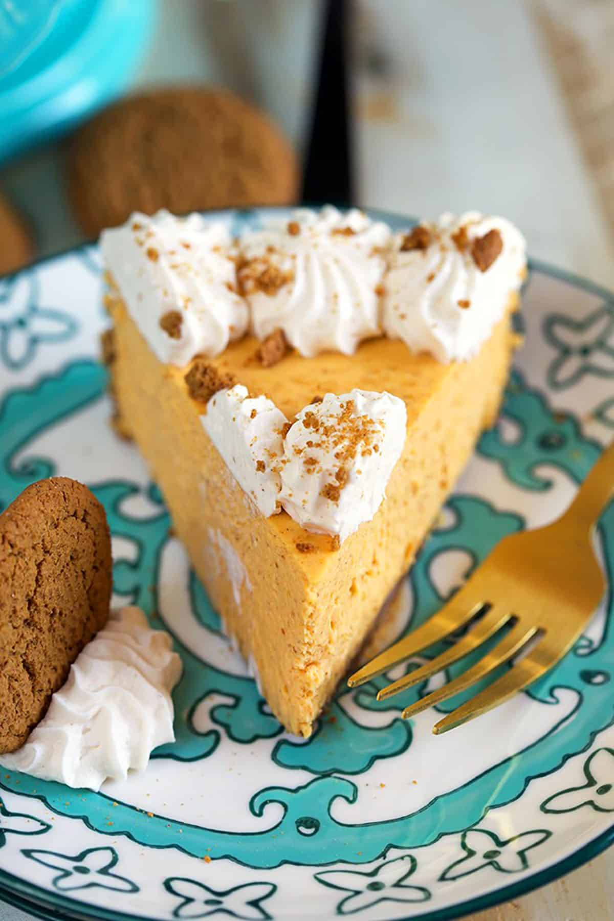 Slice of Pumpkin cheesecake on a decorative plate with a gold fork.