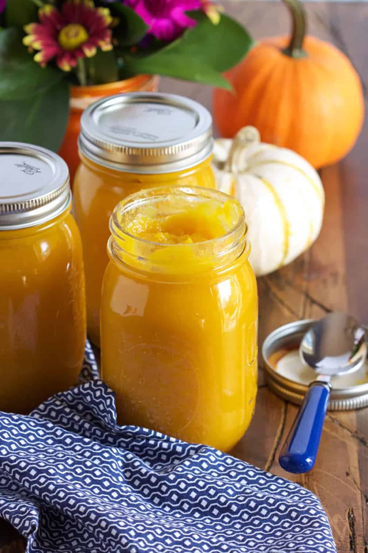 Pumpkin Puree in a ball jar with a blue and white napkin and flowers in the background.
