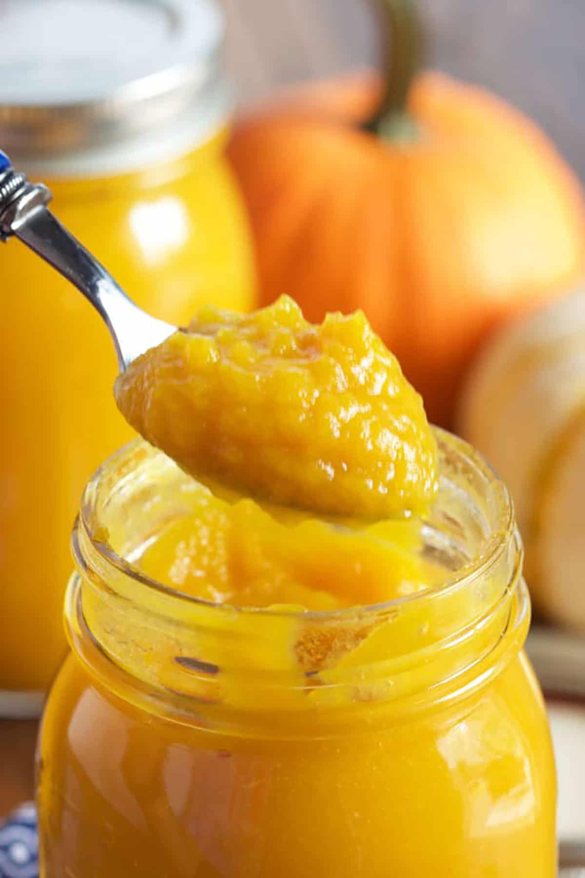 Pumpkin Puree on a spoon above a jar of pumpkin puree