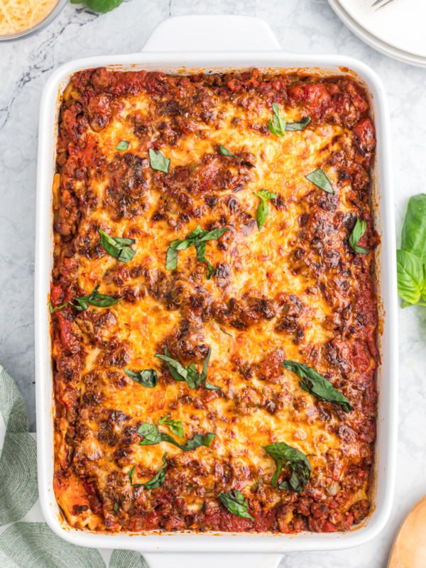 A white baking dish is filled with baked ravioli lasagna.