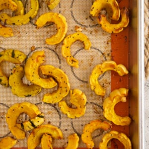 Overhead view of roasted delicata squash on a silpat-lined sheet pan