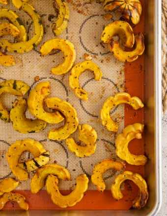 Overhead view of roasted delicata squash on a silpat-lined sheet pan