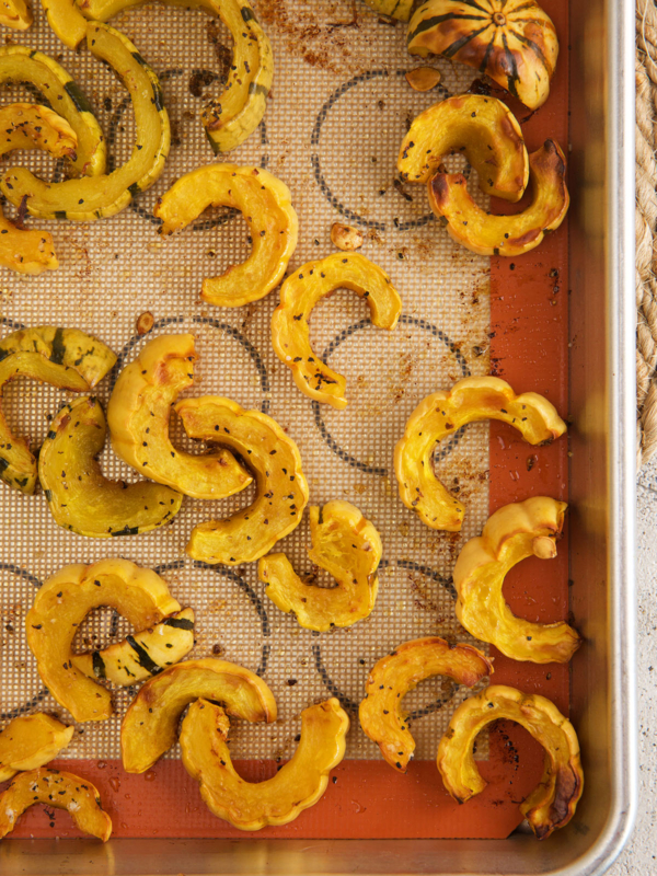 Overhead view of roasted delicata squash on a silpat-lined sheet pan