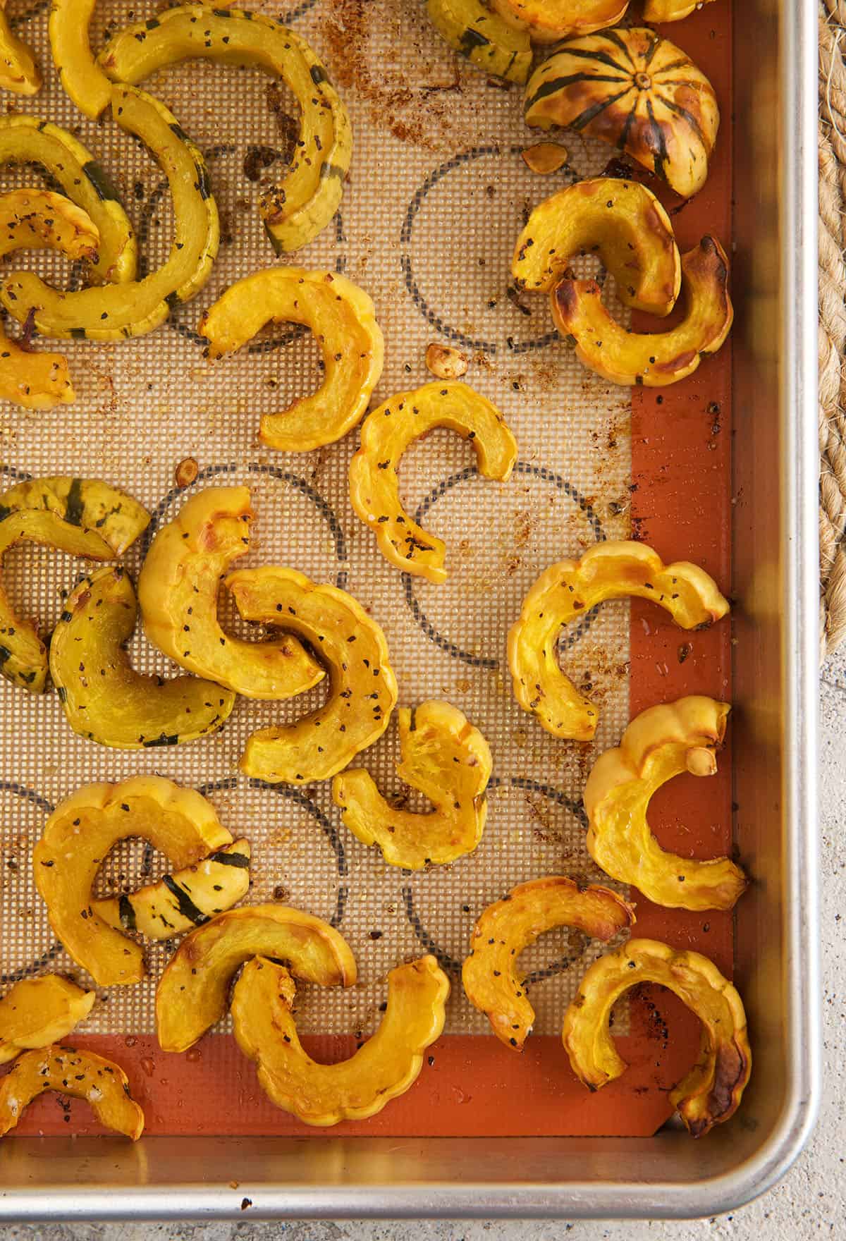 Overhead view of roasted delicata squash on a silpat-lined sheet pan