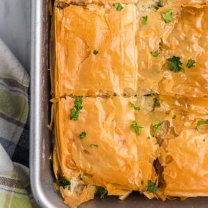 Slices of spanakopita are in a metal baking dish.