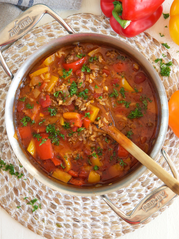A pot of soup is being stirred by a wooden spoon.