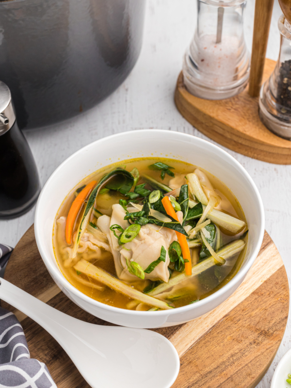 A white bowl is filled with wonton soup.