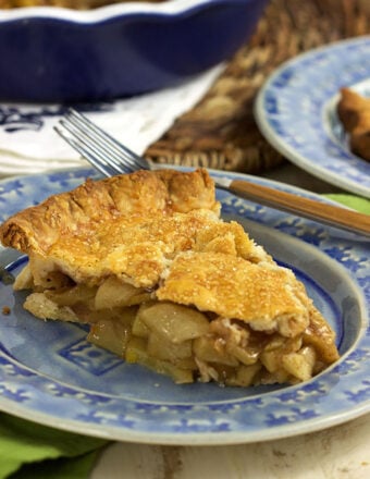 A slice of apple pie is presented on a blue and white plate.