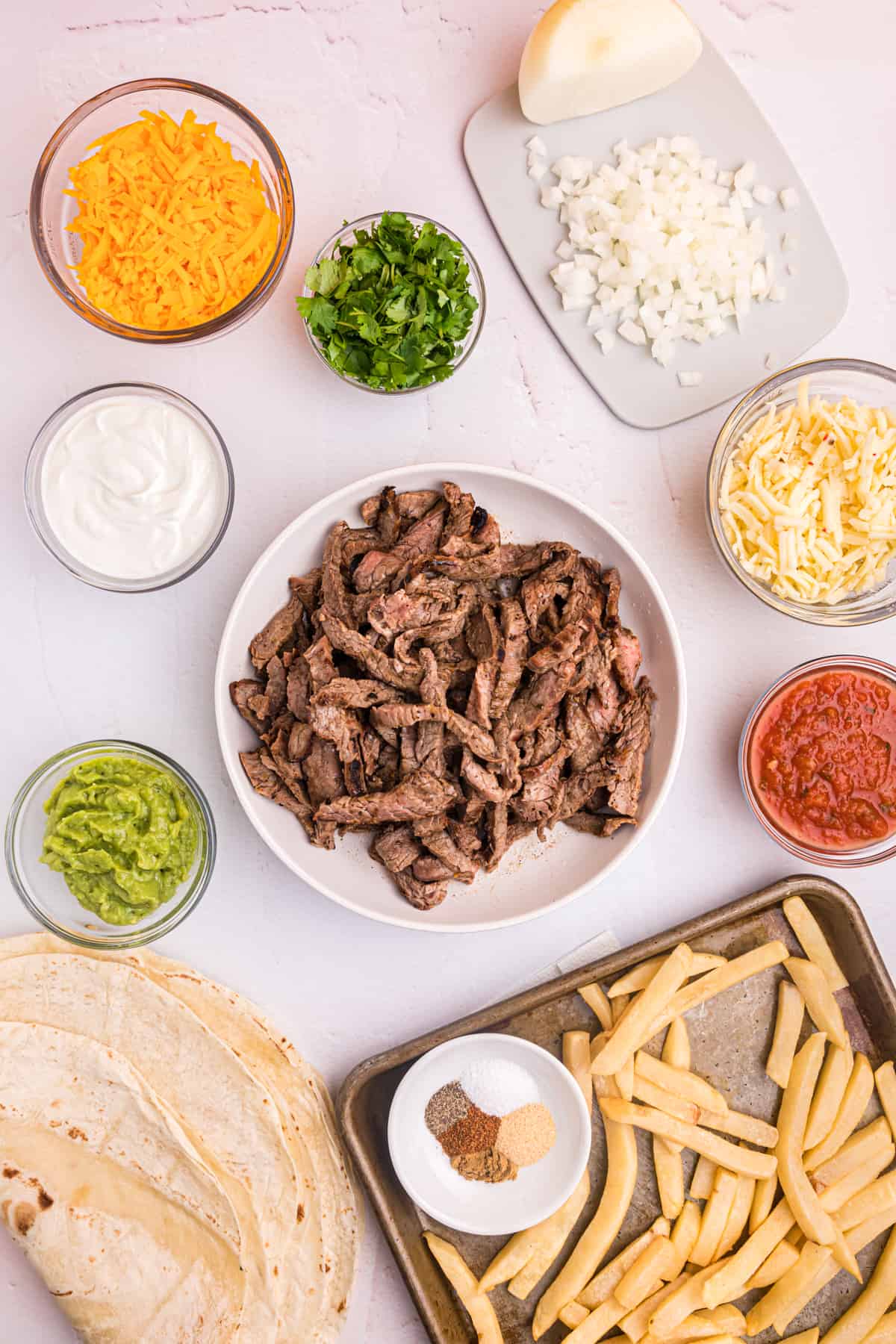 The ingredients for a california burrito are placed on a white countertop.